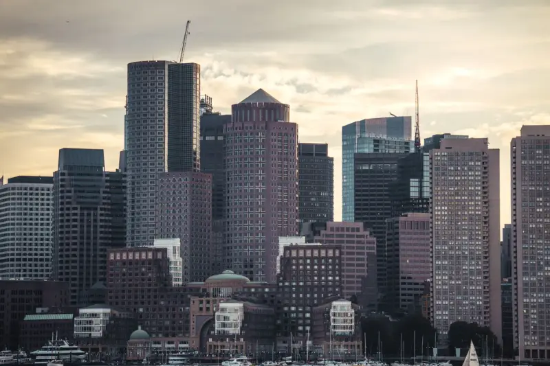 Boston skyline of high-rise towers across the harbor at dusk