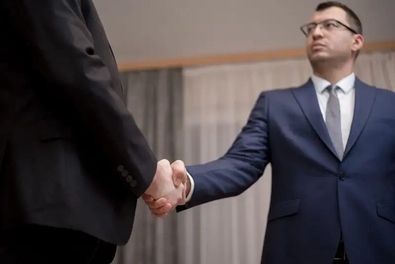 Businessmen in suits shaking hands at a meeting