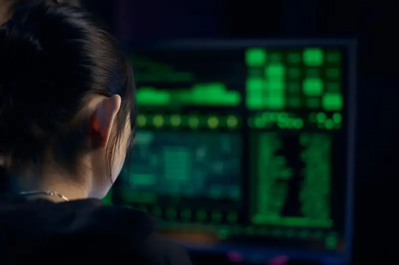 Woman studying data on a computer screen in a darkened room