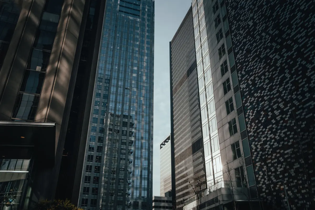 Glass and stone office towers rising toward a narrow strip of blue sky downtown