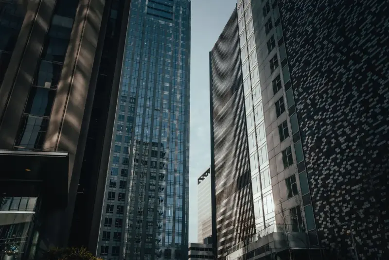 Glass and stone office towers rising toward a narrow strip of blue sky downtown