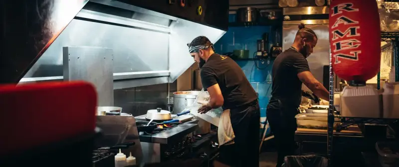 Two cooks working at a stainless steel range and prep line in a restaurant kitchen