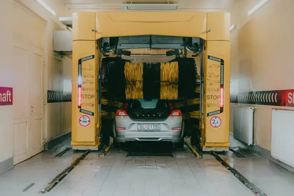 Car beneath a yellow gantry in an automated wash bay