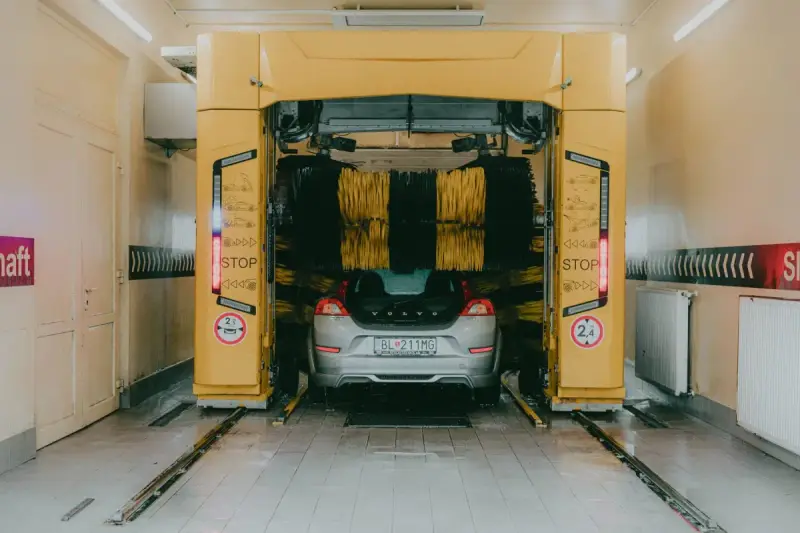 Car beneath a yellow gantry in an automated wash bay