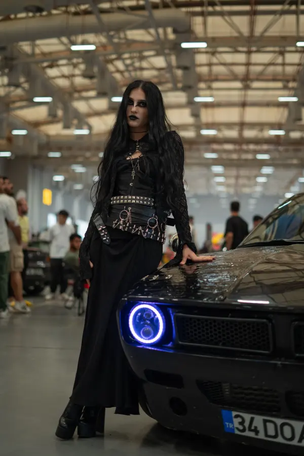 An adult woman beside a muscle car at an indoor automotive exhibition