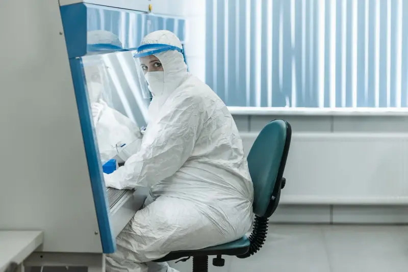 Scientist in full protective suit working at a biosafety cabinet