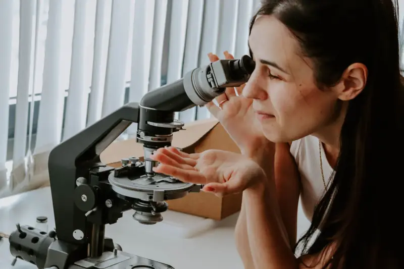 Woman researcher looking into a microscope at a lab bench