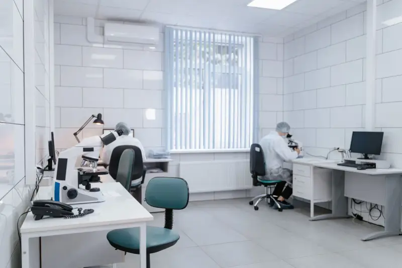 Bright white laboratory with microscopes, workstations and researchers in protective gear