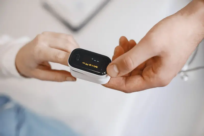 Fingertip pulse oximeter clipped on a finger showing oxygen saturation and pulse