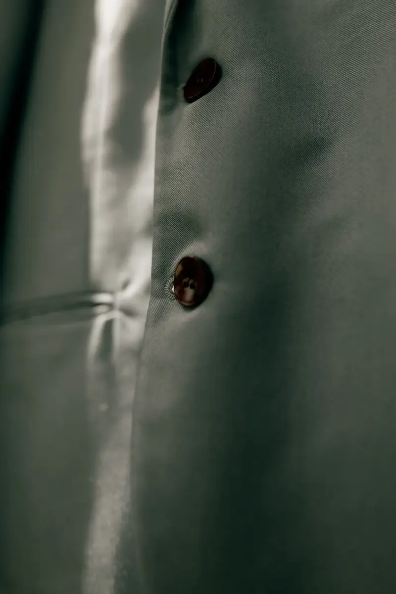 Close-up of horn buttons on a sage green wool suit jacket in soft light