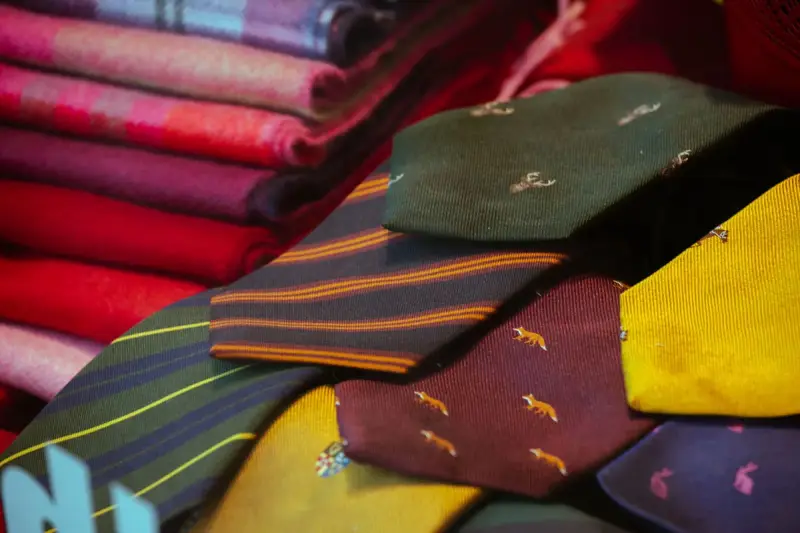 Patterned silk ties laid out beside folded wool suiting fabrics