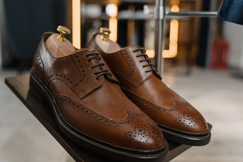 Brown leather brogues with perforated detail on a display stand