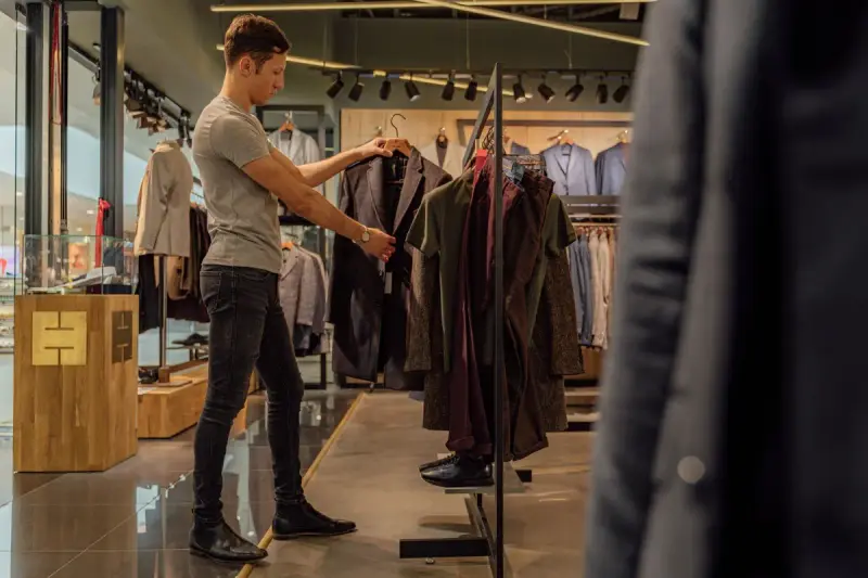 A man browses blazers hanging on a rail in a clothing store