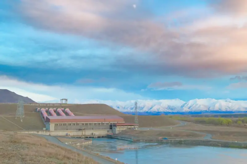 Hydroelectric station with penstocks and transmission lines below snowy mountains