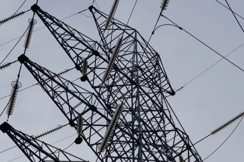 Low angle view of a steel transmission tower and cables against a clear sky