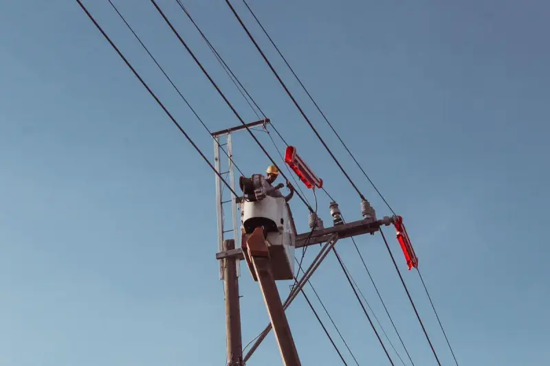 Line worker on a hoist repairing high power lines