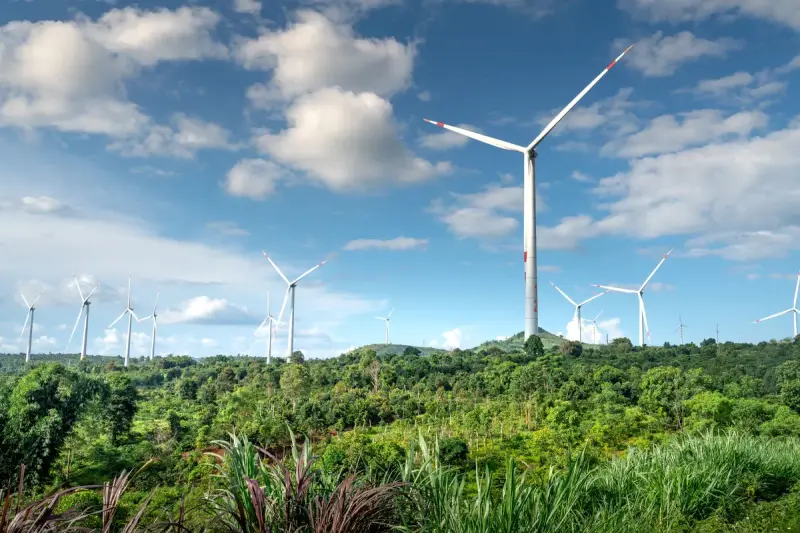 Wind turbines across a green summer landscape with clouds