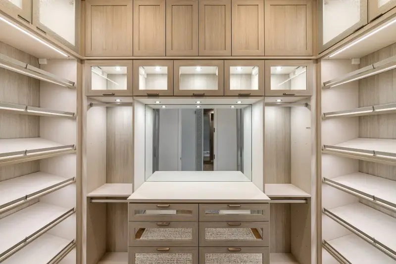Walk-in closet with light wood cabinetry, lit shelves and a center island