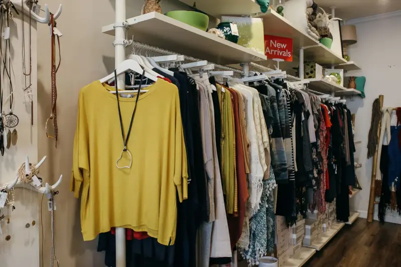 Clothing neatly hung on racks and shelves inside a light-filled boutique