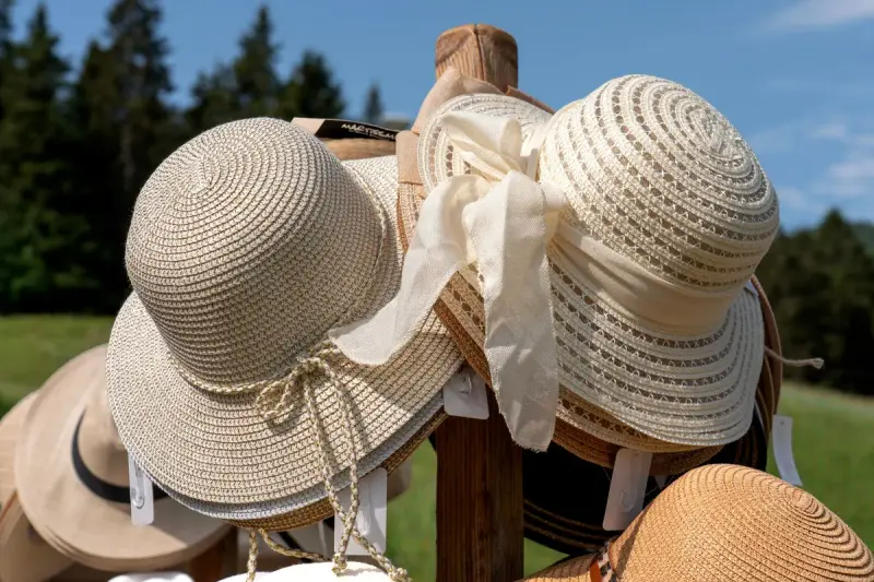 Wide-brimmed sun hats displayed on a wooden stand in sunshine