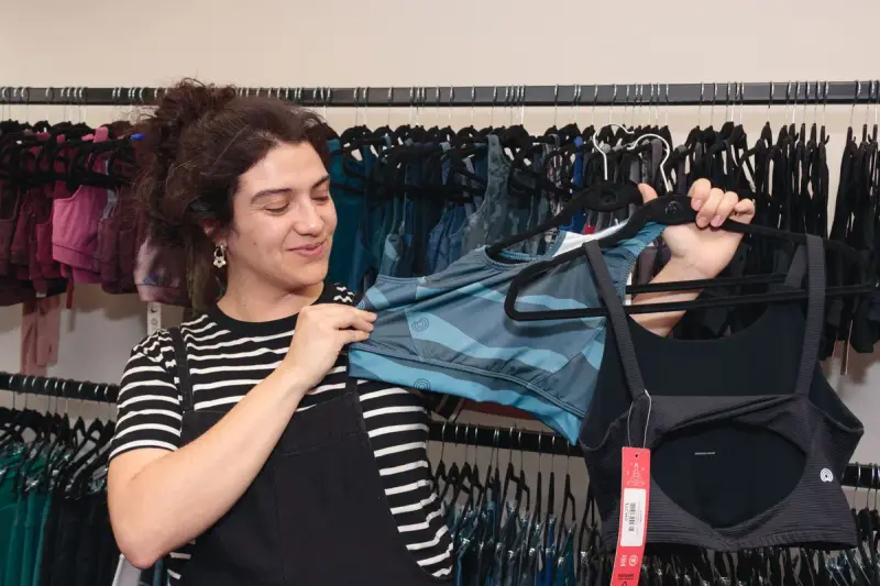 A woman browses athletic tops on a rack in a bright boutique