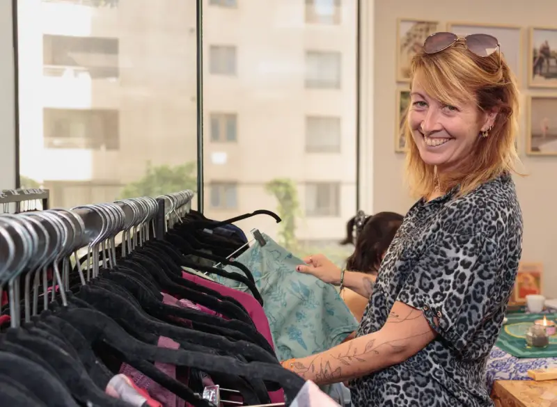 A smiling woman looks through clothes on a rack in a boutique