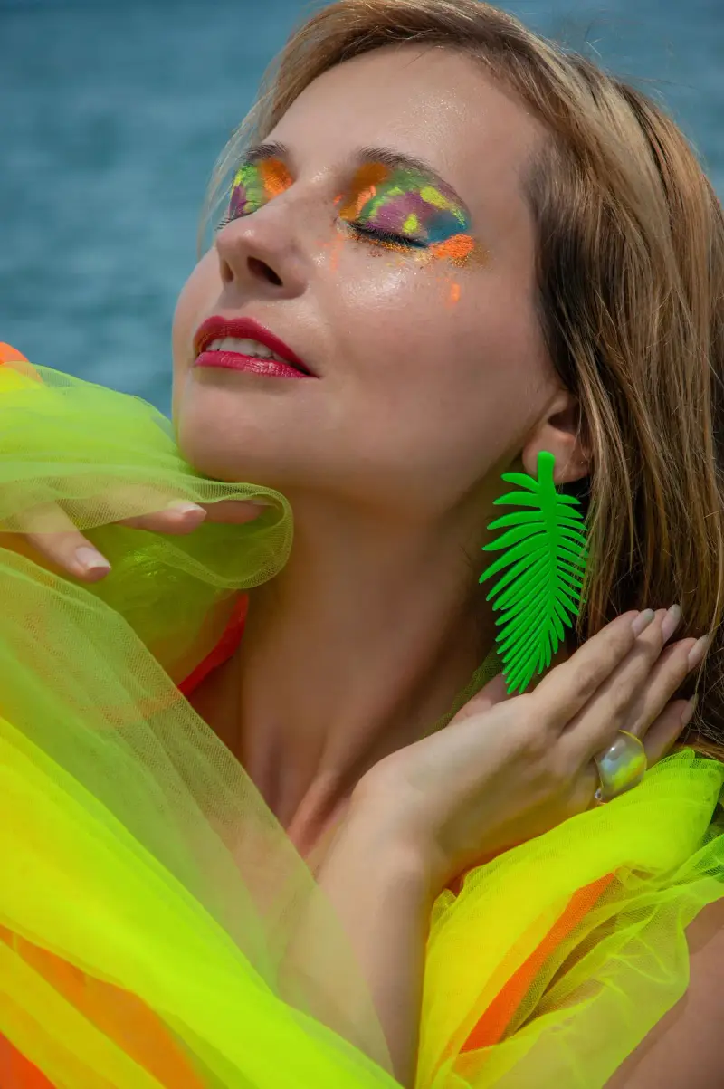 Woman with neon green and orange eye makeup wrapped in bright tulle