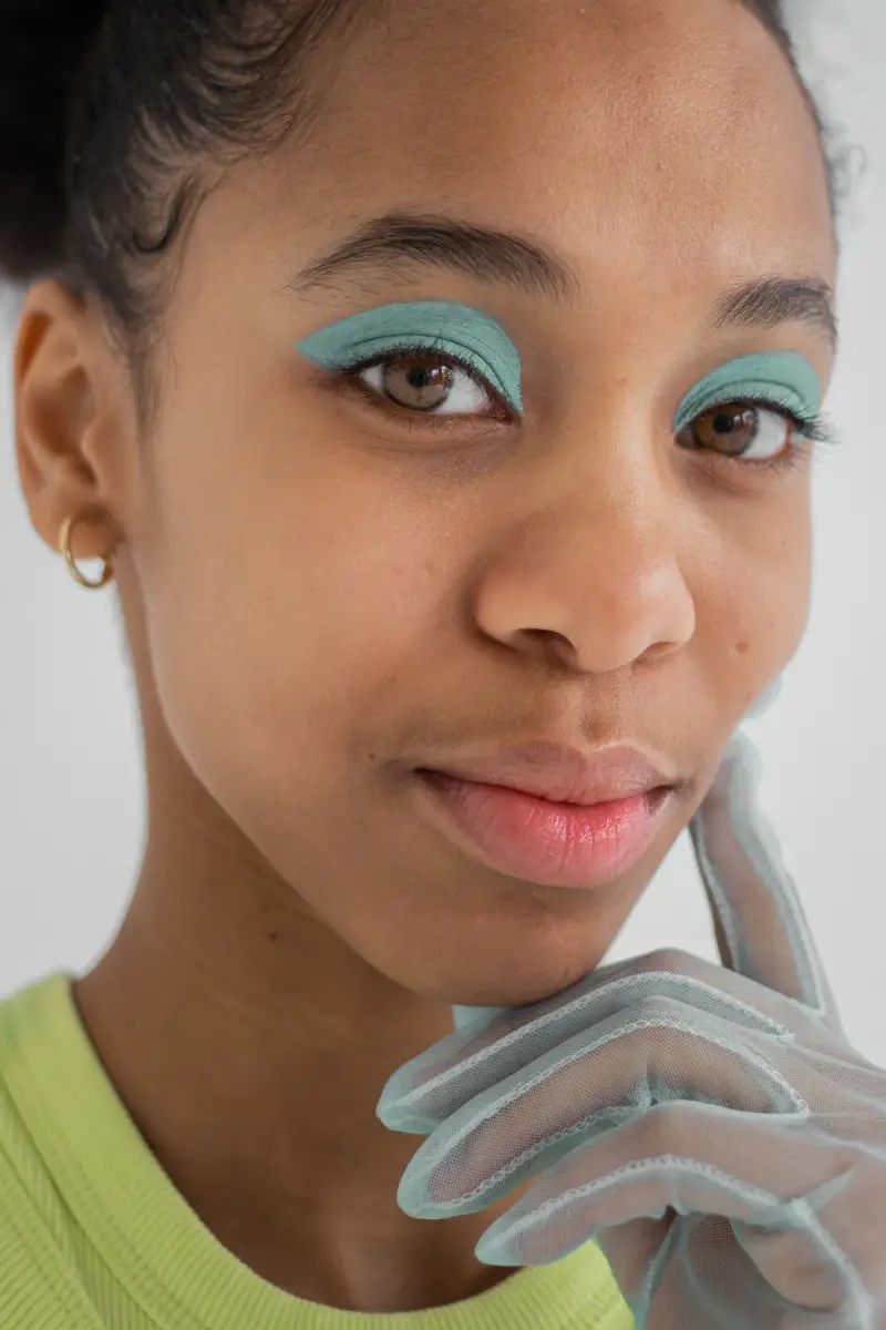 Woman with mint green eyeshadow wearing sheer gloves
