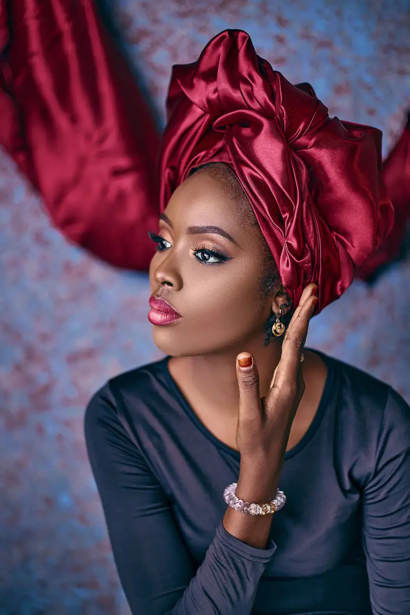 Woman in a satin burgundy headwrap with glossy lips and soft eyeshadow