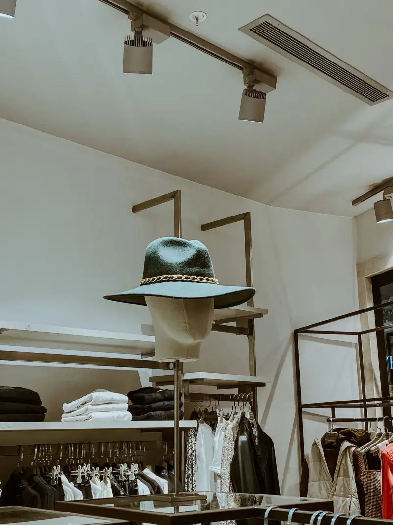 Green felt hat on a display head in a minimal boutique with brass fixtures