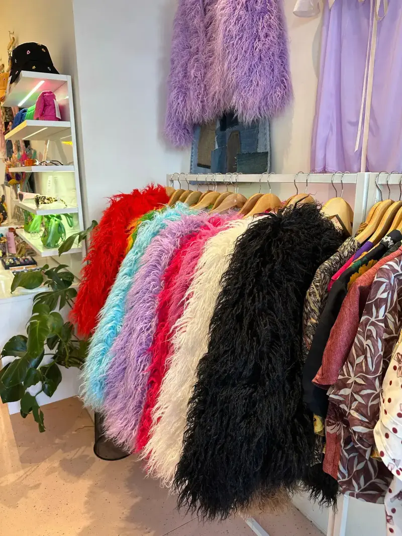 Faux fur coats in red, blue, lilac and black on a boutique rail