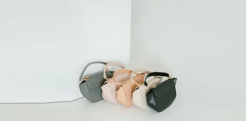 Pastel leather handbags lined up against a white backdrop