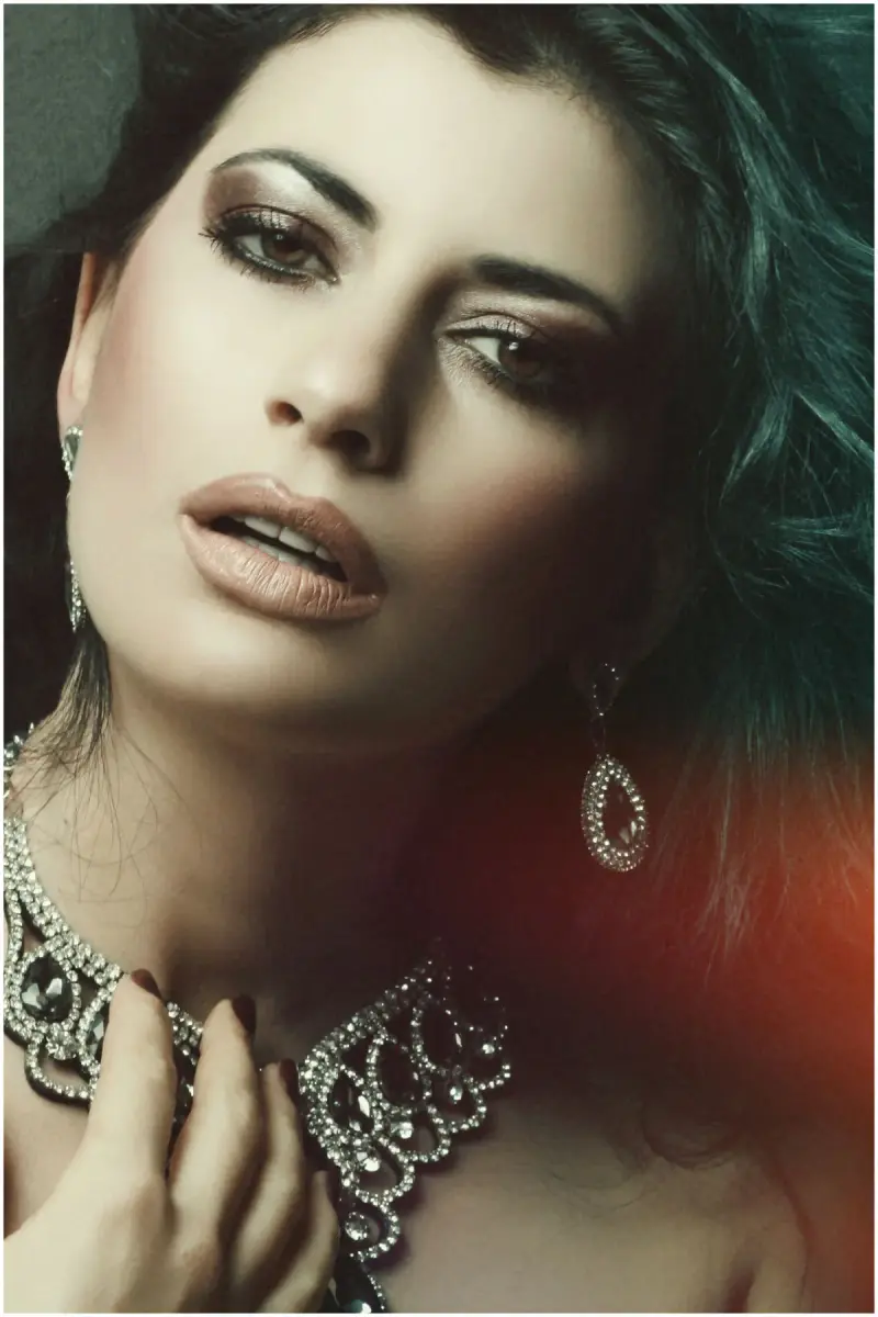 Close-up portrait of a woman wearing an ornate diamond collar necklace and teardrop earrings