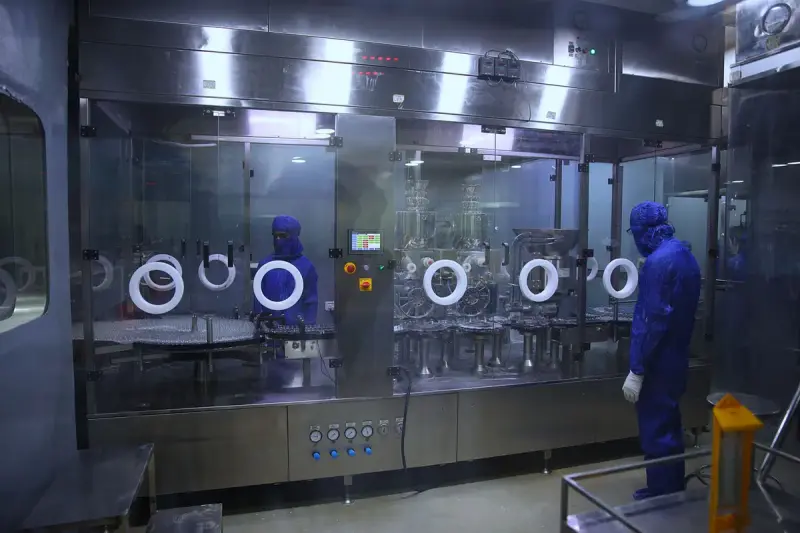 Workers in protective gowns inside a sterile pharmaceutical manufacturing plant