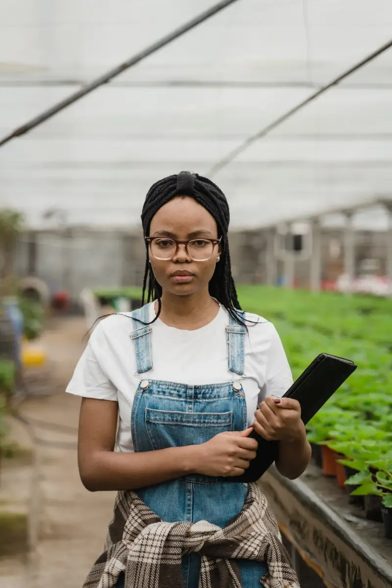 Woman horticulturist holding a clipboard while checking plants in a greenhouse