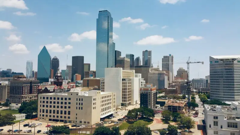 Aerial view of downtown Dallas towers and low buildings under a blue sky