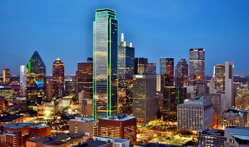 Dallas skyline at dusk with lit towers including the green-outlined Bank of America Plaza