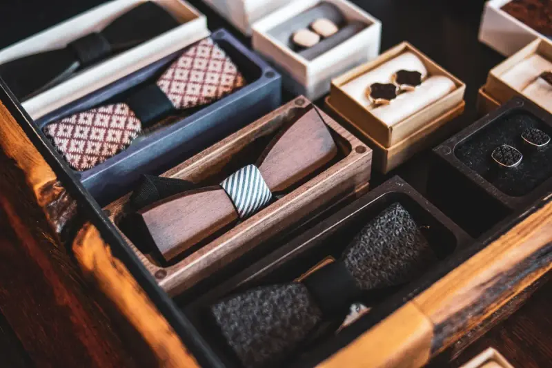 Open drawer of wooden bow ties and cufflinks in small display boxes