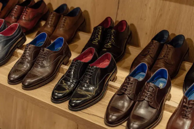 Black and brown leather oxford and derby shoes lined up on a wooden store shelf