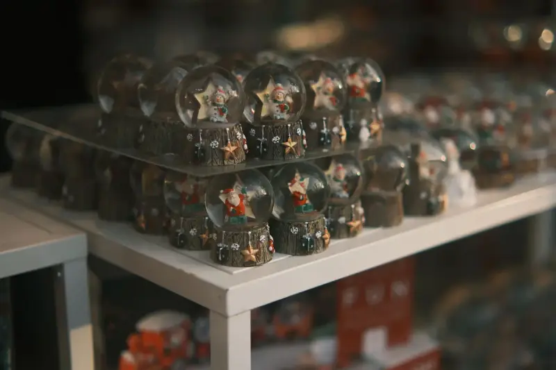 Rows of glass snow globes with Santa Claus figures on a white store display
