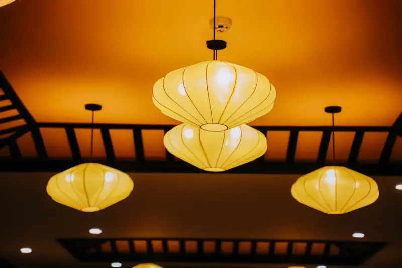 Three glowing fabric pendant lanterns hanging from a warm amber ceiling