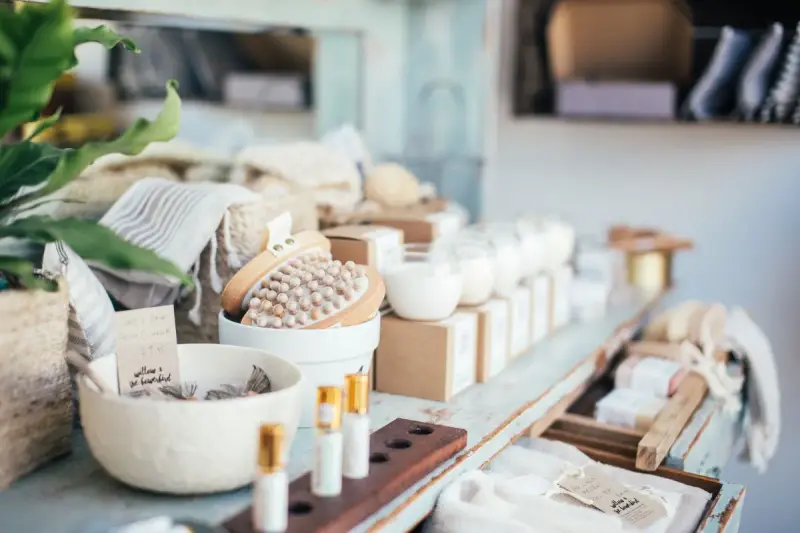 Bath brushes, soaps, candles and small perfume bottles arranged on a white shop table