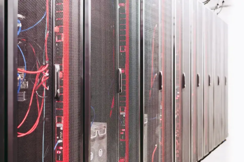 Row of mesh-door server cabinets with red and blue cabling visible inside
