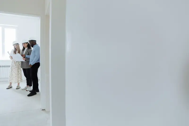 Architects in hard hats review a drawing inside a building under construction