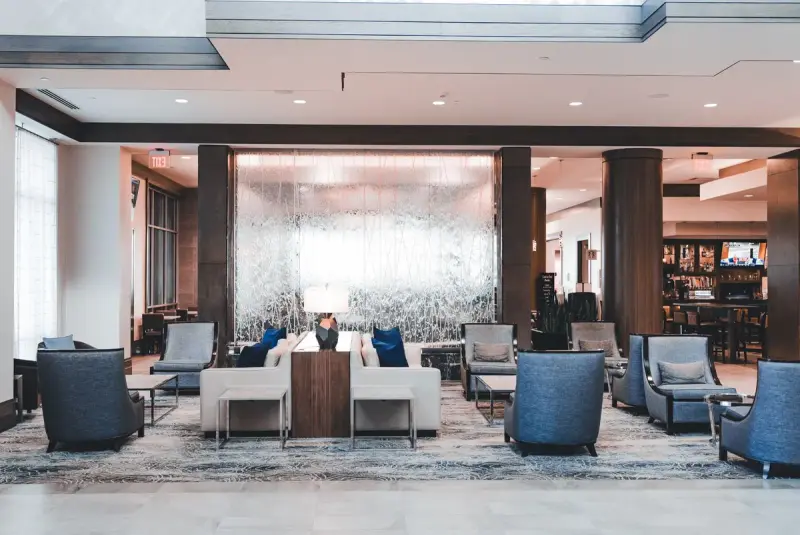 Spacious hotel lobby lounge with armchairs and sofas under a high ceiling