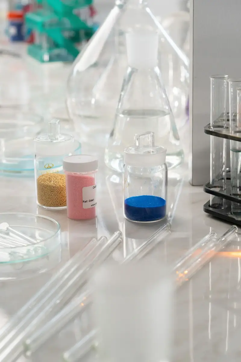 Small glass containers of colored powders beside flasks and test tubes
