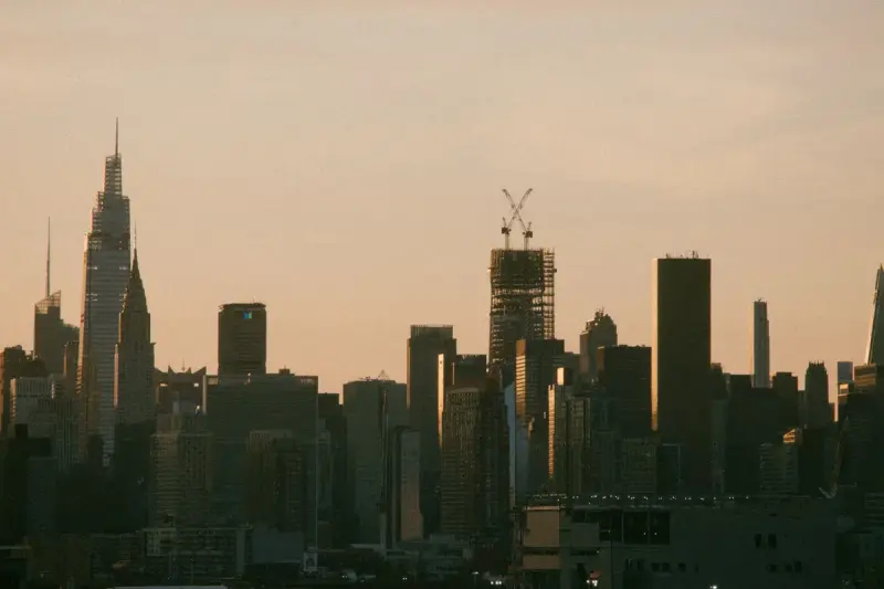 Silhouetted Midtown Manhattan towers against a warm dusk sky