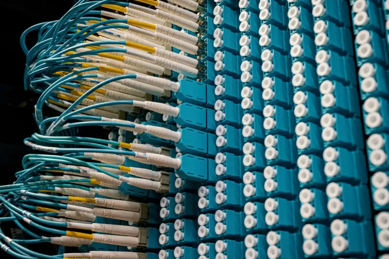 Dense fiber optic chassis with teal cables plugged into rows of connectors