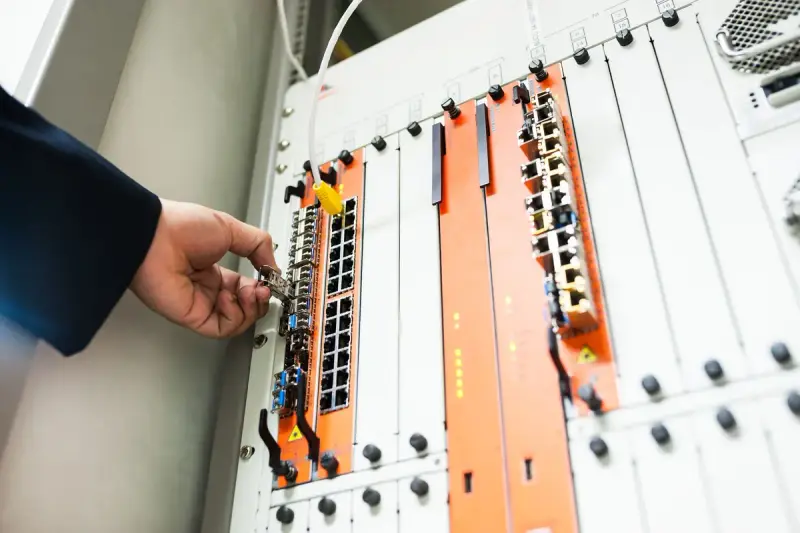 Hand adjusting a module in a network chassis with orange and white cards