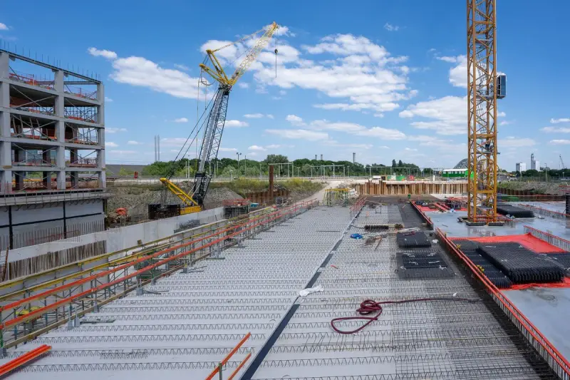 Concrete deck of a large building under construction with cranes and steel framing